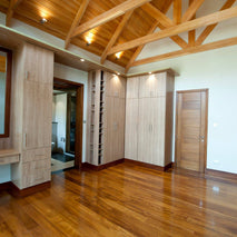 Wooden Mvule floor interior with high ceiling, large mirror, and built-in cabinets.